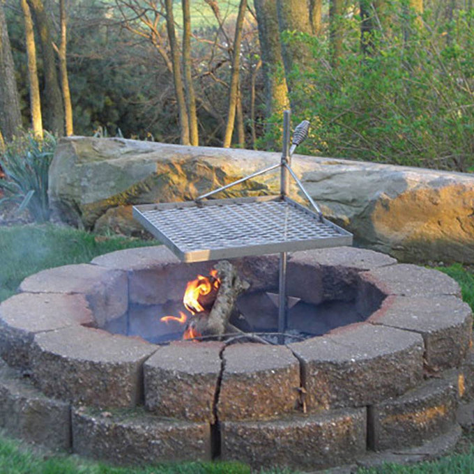 Outdoor stone fire pit with a sturdy metal grilling grate and adjustable support post, designed for durable campfire cooking in Farm, Garden & Tool, Camping, and Grilling collections.
