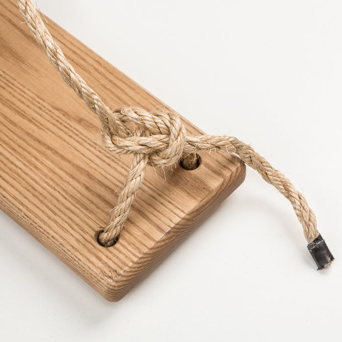 Close-up of a handcrafted wooden swing seat with natural rope securely knotted through smooth holes, part of USA Made wooden toys, outdoor play, and children’s collections.