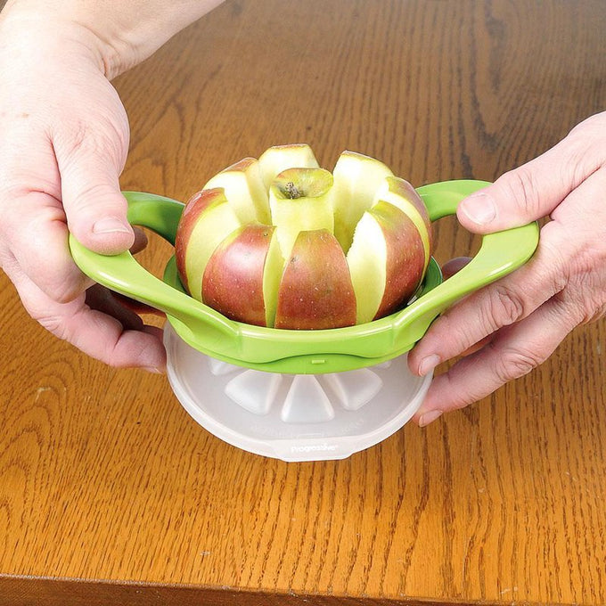 Hands pressing down on a green plastic apple cutter slicing an apple into eight wedges, designed for easy fruit preparation and featured in Kitchen & Food, Apple Harvest Supplies, and Best Sellers collections.