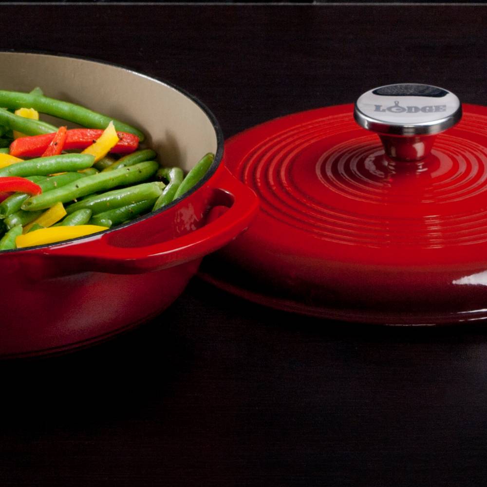 Handcrafted red enameled cast iron Dutch oven with lid featuring a polished metal knob engraved with Lodge, filled with cooked green beans and sliced bell peppers, ideal for Kitchen & Food, Cookware, Cast Iron, Best Sellers, Bread Making Supplies, and Promo Eligible collections.
