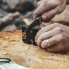 Close-up of hands using a compact Work Sharp Pivot Knife Sharpener on a folding knife blade set on a tree stump, suited for Farm, Garden & Tool and Knives & Axes sharpening tasks.