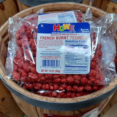 Clear plastic bag filled with vibrant red candy-coated French burnt peanuts resting on a rustic wooden barrel, featured in Kitchen & Food, Candy, USA Made, and Best Sellers collections.