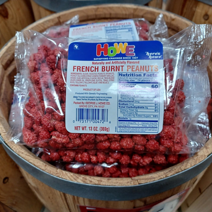 Clear plastic bag filled with vibrant red candy-coated French burnt peanuts resting on a rustic wooden barrel, featured in Kitchen & Food, Candy, USA Made, and Best Sellers collections.
