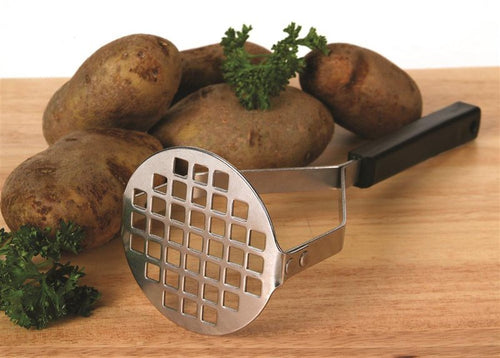 Heavy-duty stainless steel potato masher with square holes and black handle resting on wooden surface with whole potatoes and fresh parsley, ideal for Kitchen & Food, Food Prep, Choppers and Cutters, Kitchen Gadgets, Cooking and Baking Helpers, USA Made, Best Sellers, and Promo Eligible collections.