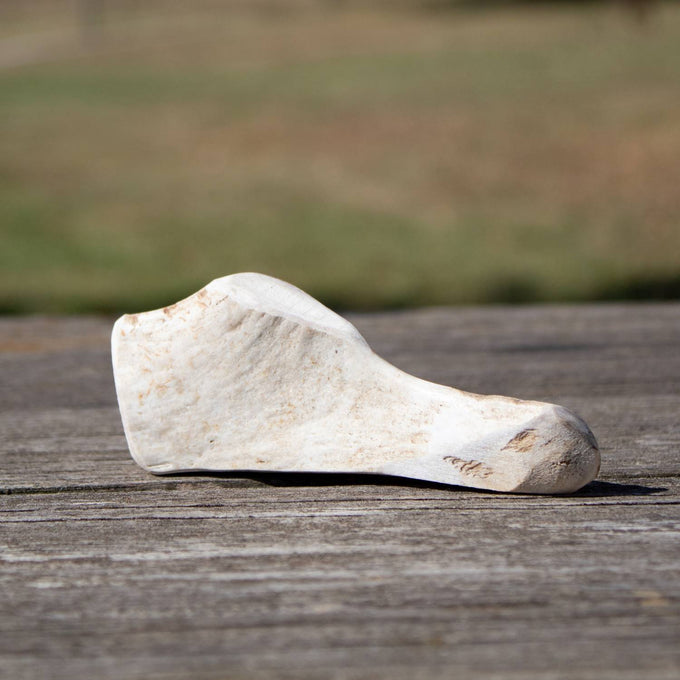 Natural split deer antler dog chew resting on weathered wood, highlighting its durable, splinter-free texture, perfect for pet supplies in USA Made and Best Sellers collections.