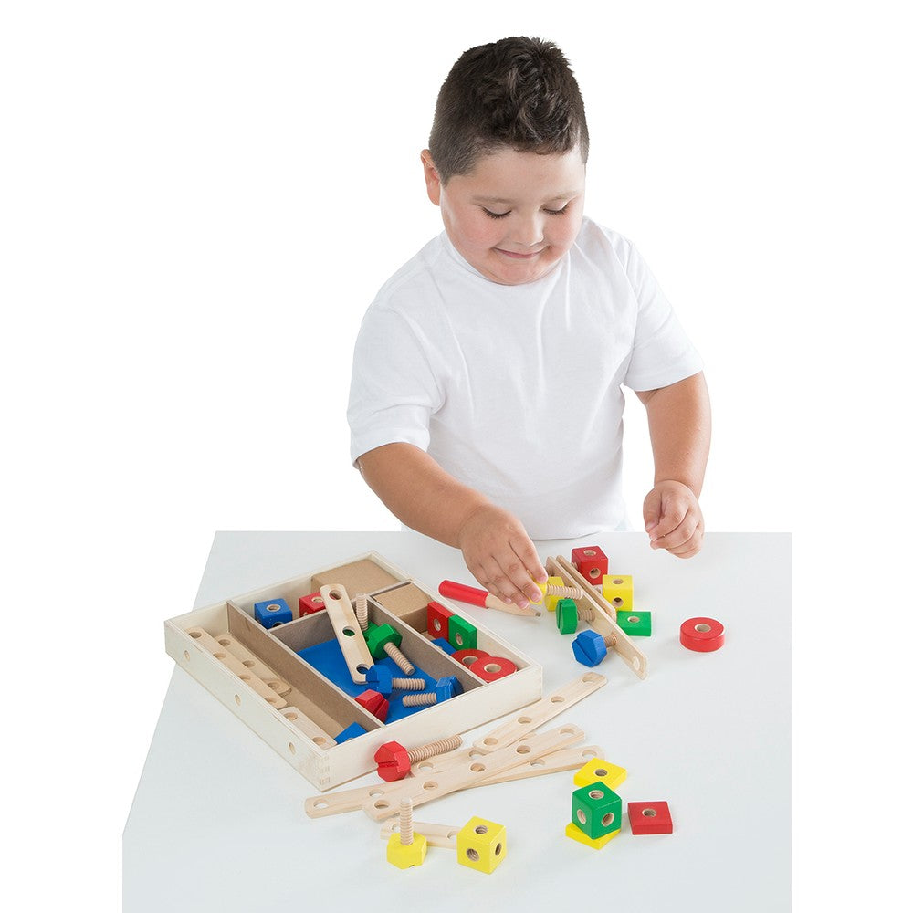 Child engaged in indoor play with a wooden construction building set featuring colorful nuts, bolts, blocks, and a child-size screwdriver from a handcrafted Toys, Books & Games collection.