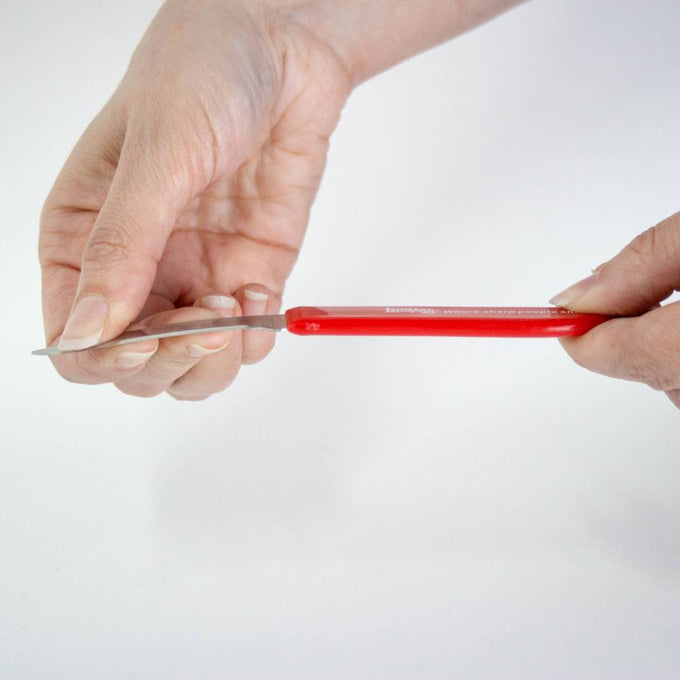 Close-up of a person holding a flexible paring knife with a bright red handle, demonstrating the blade’s flexibility, part of kitchen and food prep tools collection.