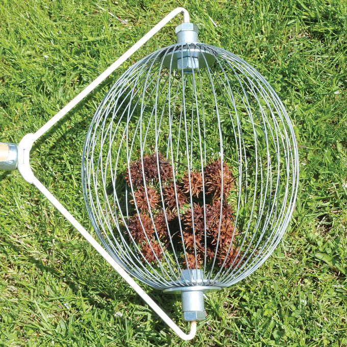 Round metal nut gatherer with wooden handle filled with sweet gum seed pods on green grass, designed to ease yard cleanup without bending; featured in Farm, Garden & Tool, Lawncare, Best Sellers, and Promo Eligible collections.