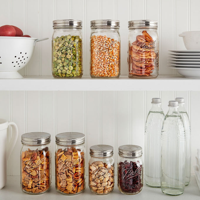 Three regular-mouth glass jars with stainless steel lids on a white shelf, filled with dried peas, popcorn, and cinnamon sticks, alongside more jars and glass bottles below, styled for Kitchen & Food, Storage and Serving, Best Sellers, and Promo Eligible collections.