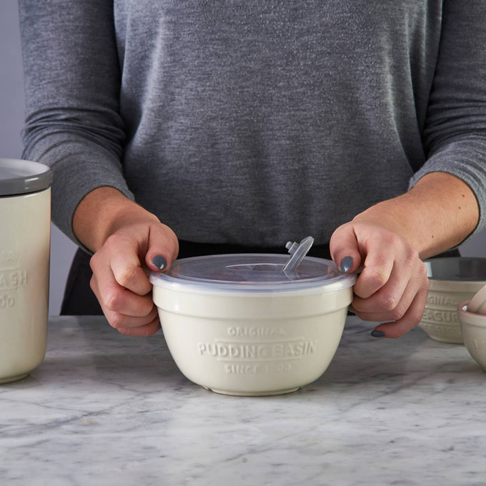 Cream-colored Mason Cash all-purpose bowl with vented airtight lid held by hands, designed for steaming and storing food, ideal for Kitchen & Food, Cookware, Baking Supplies, Storage and Serving, Best Sellers, Promo Eligible collections.