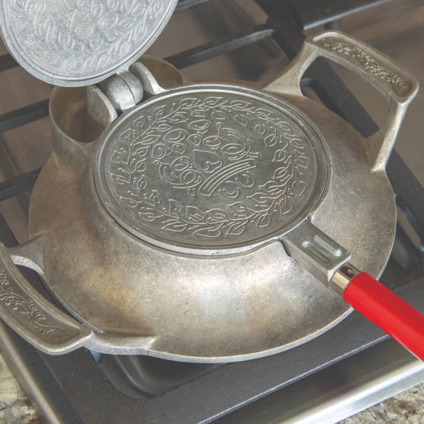 Stovetop iron with aluminum base and red wooden handle, featuring detailed patterned plates for making traditional cookies, crafted in USA for Kitchen & Food and Baking Supplies collections.