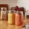 Three wide-mouth glass jars with stainless steel lids, storing dry pantry goods on a wooden countertop, highlighting airtight storage ideal for Kitchen & Food and Storage and Serving collections.