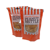 Two resealable orange and white striped bags of handmade peanut brittle featuring gluten-free and preservative-free labels, perfect for Kitchen & Food and USA Made collections.