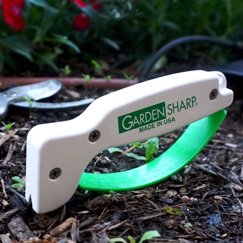 Compact garden tool sharpener with white body and green handle, featuring a reversible diamond-honed tungsten carbide edge, made in USA for Farm, Garden & Tool and Lawncare collections.