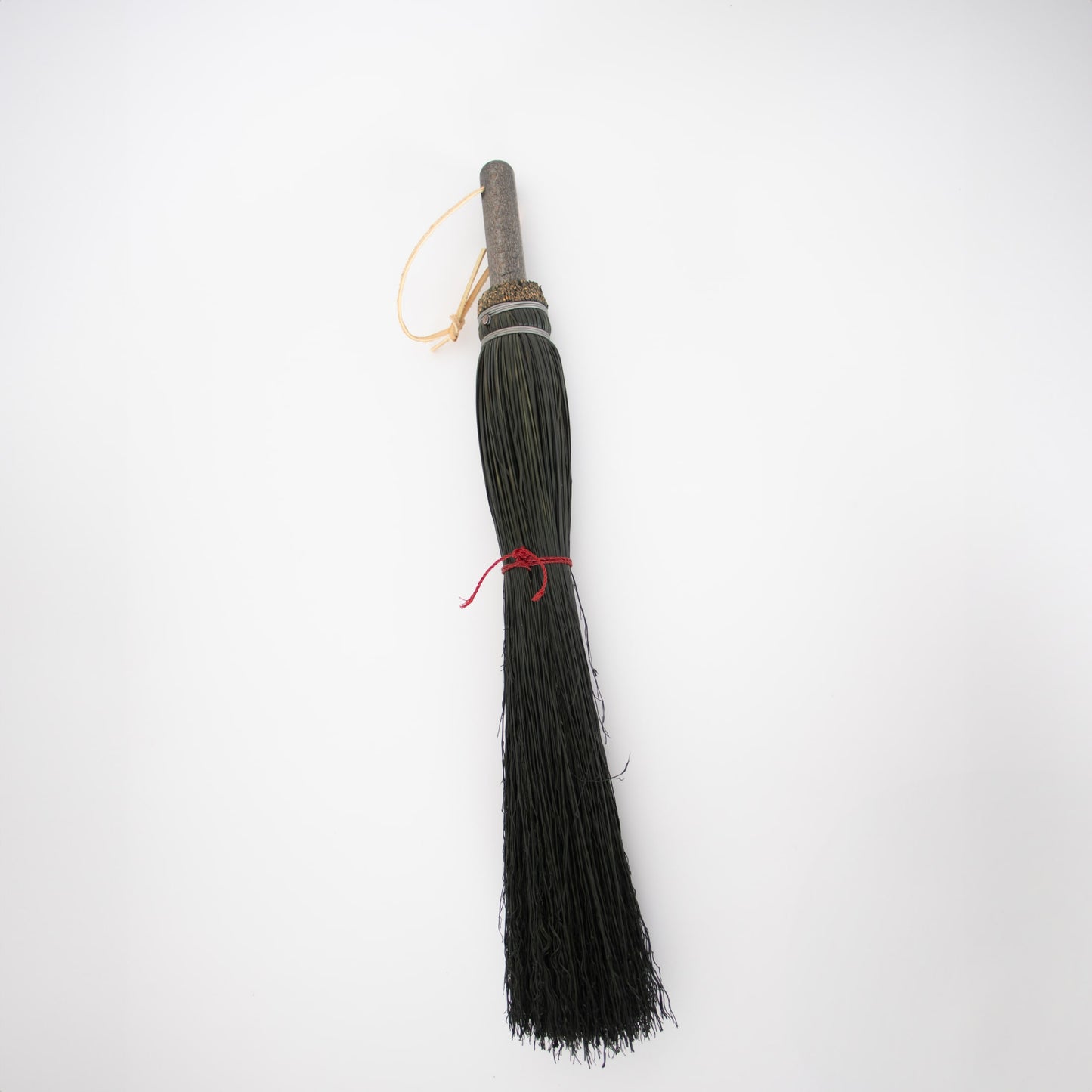 Handmade small broom with long, thin black bristles bound with metal bands and a wooden handle, crafted in the USA, ideal for cleaning stoves and hearths.