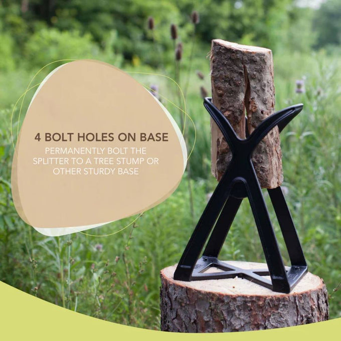 Black metal kindling splitter with wide mouth design holding a thick log upright on a tree stump, featuring four bolt holes for secure mounting, set outdoors in a grassy field.