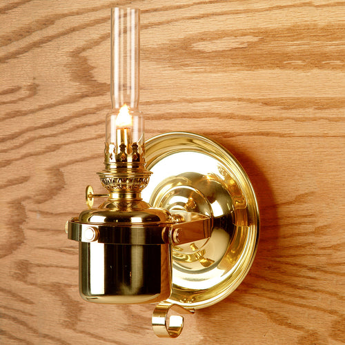 Handcrafted brass gimbaled oil lamp mounted on a wood wall, featuring a clear glass chimney and steady flame, ideal for lamps & lighting, oil lamps, and table lamp collections.