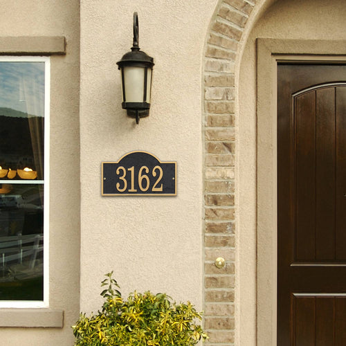 Handcrafted black and gold arched rectangle address plaque mounted on a light stucco wall next to a dark brown front door and outdoor lantern, featured in Home & Decor, Household Helpers, Mailboxes and Address Signs, USA Made, Best Sellers, and Promo Eligible collections.