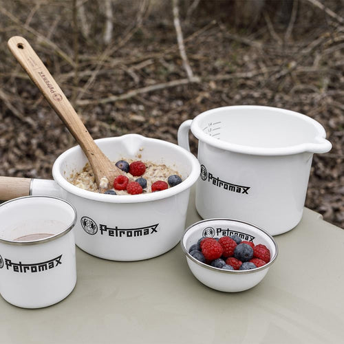 Set of white enameled steel cookware including a milk pot with spout, a bowl of oatmeal with berries and wooden spoon, a small bowl with berries, and a cup, handcrafted for Farm, Garden & Tool, Kitchen & Food, Camping, Cookware, Pots and Pans, Best Sellers, and Promo Eligible collections.