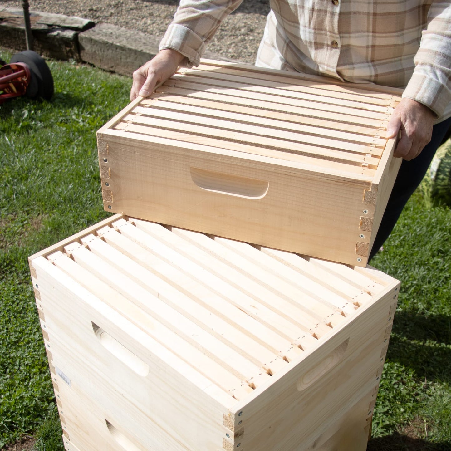 Amish-made natural wood beehive frames stacked outdoors with a person assembling, highlighting quality craftsmanship for Farm, Garden & Tool, Beekeeping Supplies, and 10-Frame Hives collections.