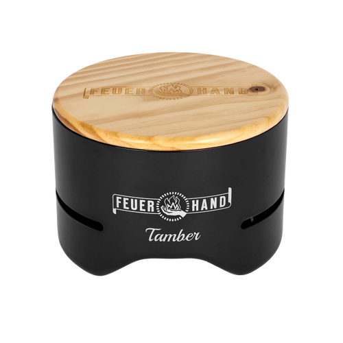 Compact black tabletop charcoal grill with a smooth wooden lid engraved with the Feuerhand logo, designed for small outdoor grilling in Farm, Garden & Tool and Camping collections.