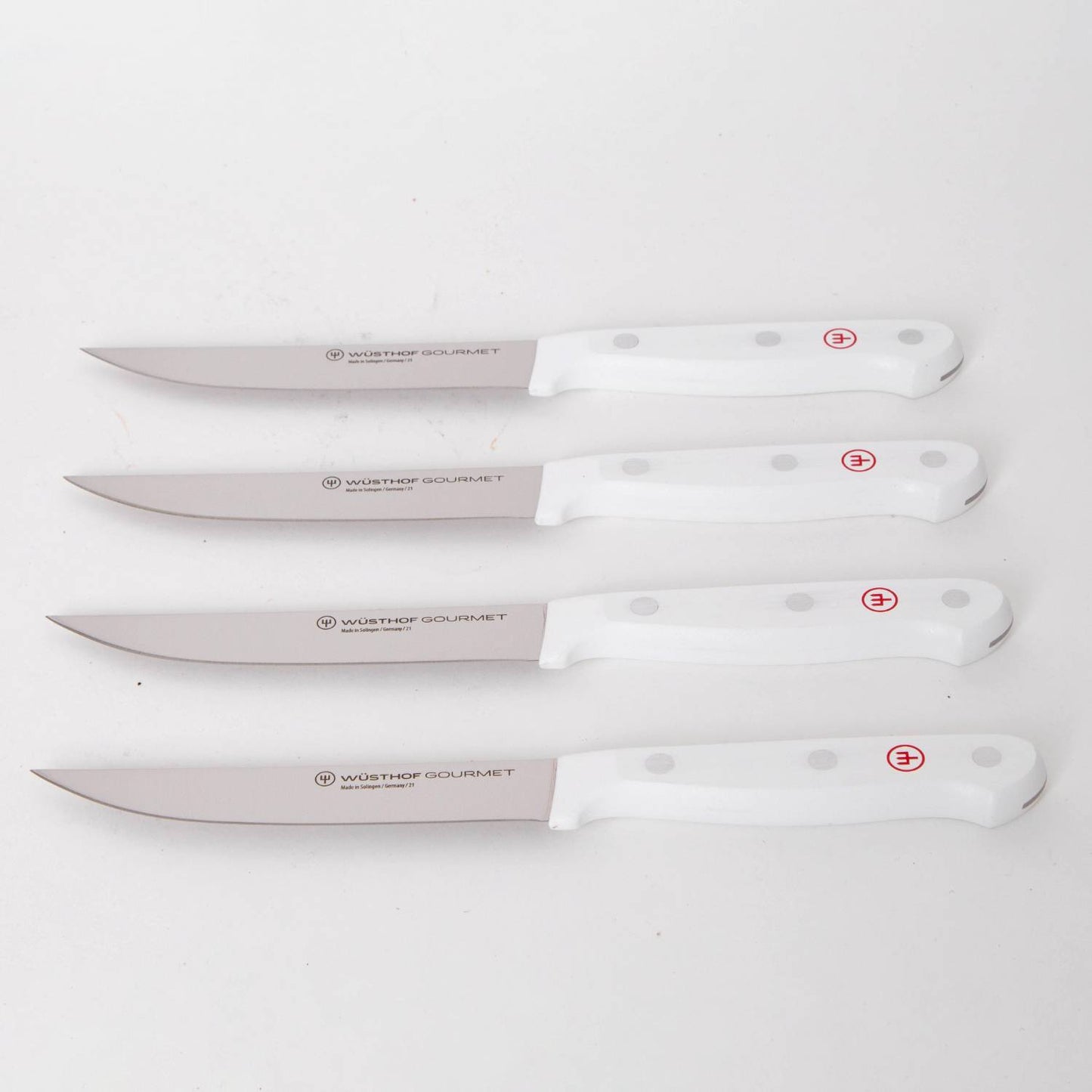 Four white-handled kitchen knives with stainless steel blades, featuring ergonomic grips and stamped logos, ideal for precision food prep in Kitchen & Food and Knives & Axes collections.