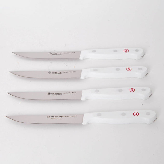 Four white-handled kitchen knives with stainless steel blades, featuring ergonomic grips and stamped logos, ideal for precision food prep in Kitchen & Food and Knives & Axes collections.