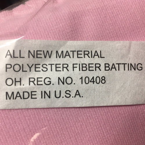 Close-up of a label on pink fabric stating the product is made in the USA with all new polyester fiber batting, highlighting quality and craftsmanship for children's toys and Amish Made collections.