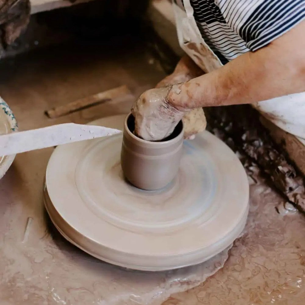 Artisan shaping a clay vessel on a pottery wheel, demonstrating handcrafted pottery techniques for durable, functional kitchen cookware in the USA Made collection.
