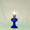 Handcrafted cobalt glass oil lamp with brass burner and tall clear chimney, featuring a vintage-inspired font design, ideal for Lamps & Lighting, Oil Lamps, Table Lamps, Best Sellers, and Promo Eligible collections.