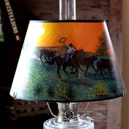 Parchment oil lamp shade with handcrafted Southwestern artwork of a cowboy riding at sunset through desert flora, designed to softly diffuse light, part of Lamps & Lighting and Best Sellers collections.
