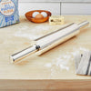 Sleek stainless steel rolling pin with nylon bearings resting on a floured wooden counter alongside flour, eggs in a wooden bowl, and unsalted butter, featured in Kitchen & Food, Cookware, Baking Supplies, and Best Sellers collections.
