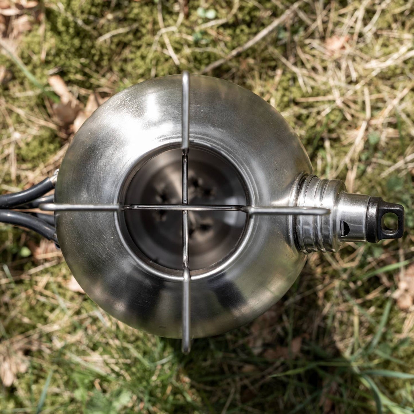 Top-down view of a handcrafted stainless steel fire kettle with integrated pot stand and screw-on spout, resting on grass; suitable for Farm, Garden & Tool, Camping, Emergency Supplies, and Best Sellers collections.