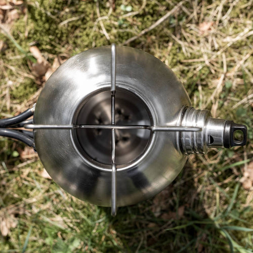 Top-down view of a handcrafted stainless steel fire kettle with integrated pot stand and screw-on spout, resting on grass; suitable for Farm, Garden & Tool, Camping, Emergency Supplies, and Best Sellers collections.