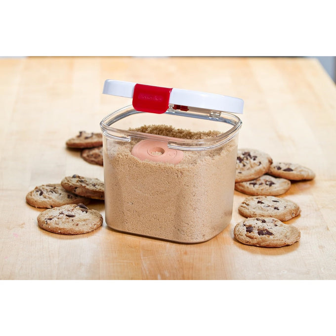 Clear plastic brown sugar keeper with a snap-shut white lid featuring a red clasp and a terra cotta moisture-control piece inside, surrounded by chocolate chip cookies, ideal for Kitchen & Food, Storage and Serving, and Best Sellers collections.