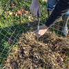 Hands using a Compost Crank Twist with stainless steel spiral and cushioned handle to aerate and mix compost inside a wire compost bin outdoors, part of Farm, Garden & Tool and USA Made collections.