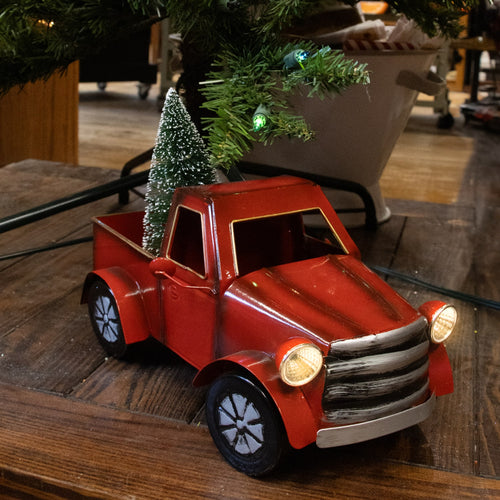 Small handcrafted red metal vintage-style holiday truck with battery-operated illuminated headlights and festive green tree in its bed, ideal for Home & Decor and Holiday Decor.