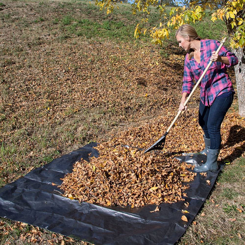Person raking fallen leaves onto a black woven polyethylene Clean Up Canvas with four reinforced soft grip handles, ideal for Farm, Garden & Tool and Lawncare collections.
