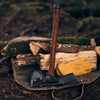 Pulaski axe with hand-sharpened 1055 high carbon steel head and smooth wooden handle, resting on canvas sheath beside yellow work gloves and split firewood, ideal for farm and garden tasks