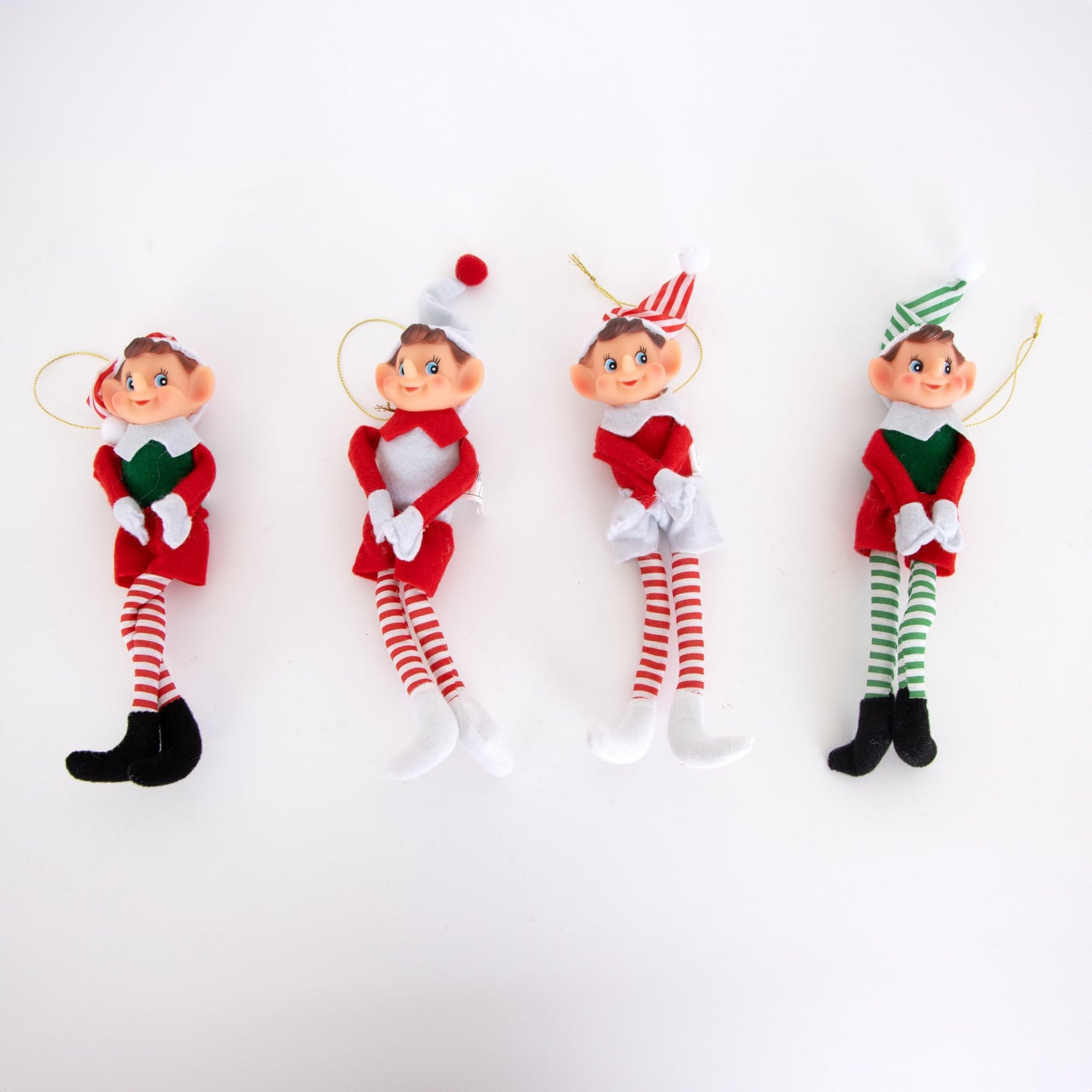 Four posable retro-style Christmas elf ornaments in red, white, and green festive outfits with striped tights, fabric bodies, and hanging cords, featured in holiday decor collections.