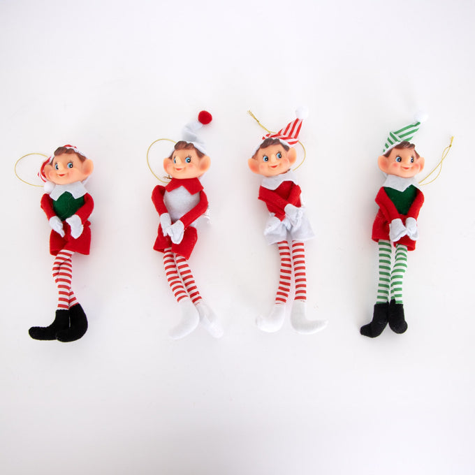 Four posable retro-style Christmas elf ornaments in red, white, and green festive outfits with striped tights, fabric bodies, and hanging cords, featured in holiday decor collections.