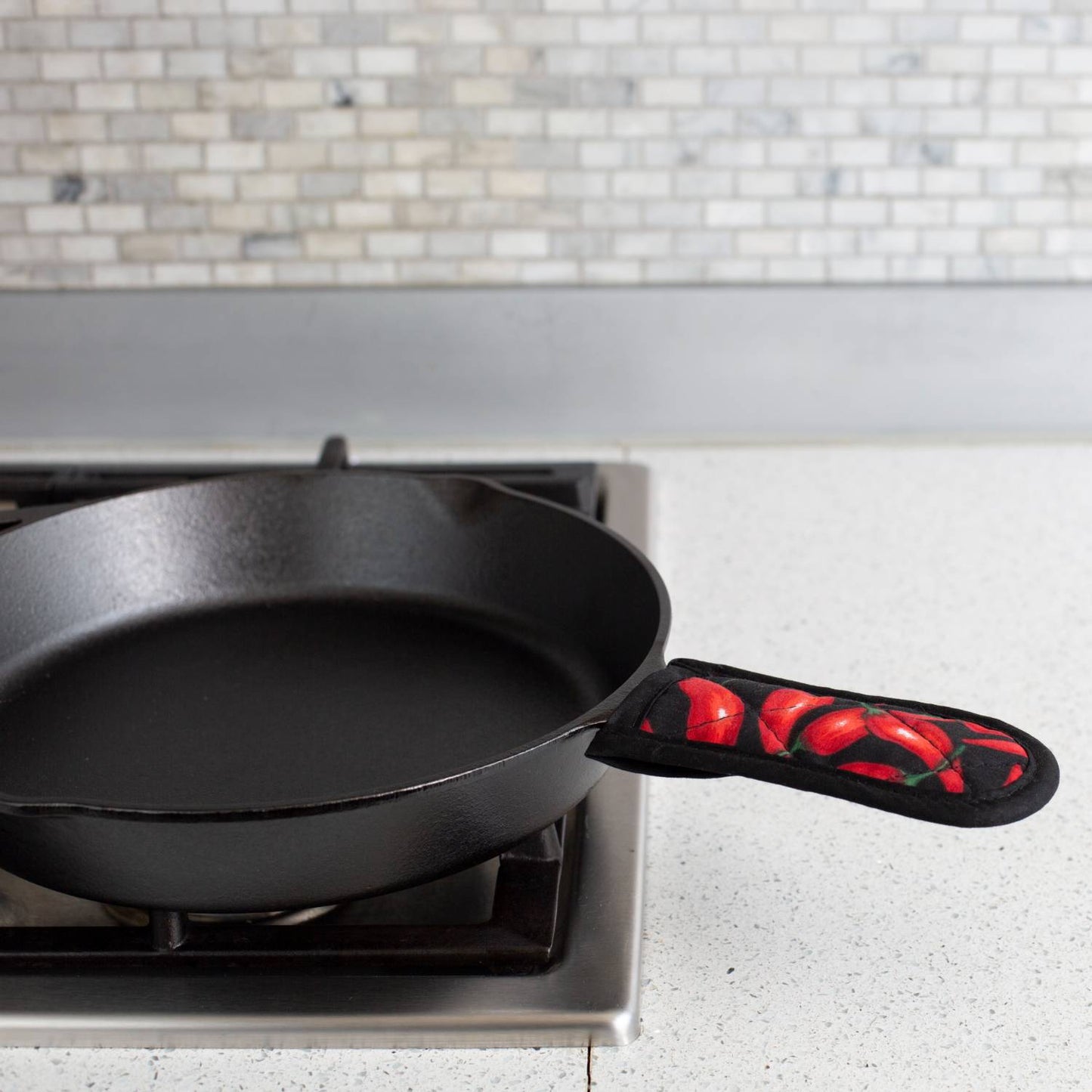 Single padded handle cover with red chili pepper design fitted on cast iron skillet handle, crafted for heat protection up to 350°F, suitable for Kitchen & Food, Cookware, Cast Iron, Best Sellers, and Promo Eligible collections.