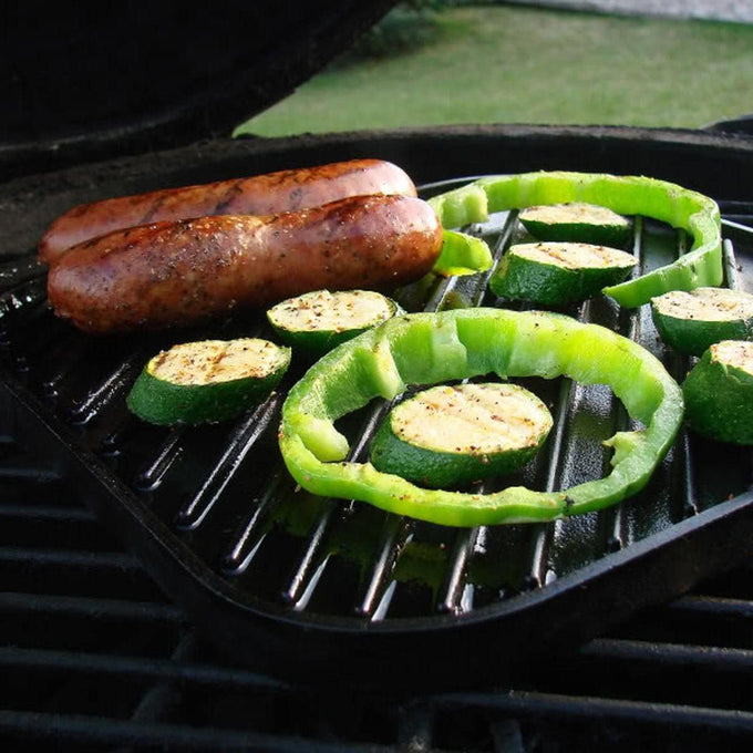 Cast iron reversible grill surface with sausages, zucchini slices, and green bell pepper rings cooking outdoors, handcrafted, ideal for Kitchen & Food, Cookware, Cast Iron, USA Made collections.