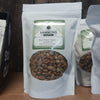 White resealable bag filled with caramelized black walnut nuggets, labeled with Hammons Pantry logo, displayed on wooden surface in Kitchen & Food snacks collection.