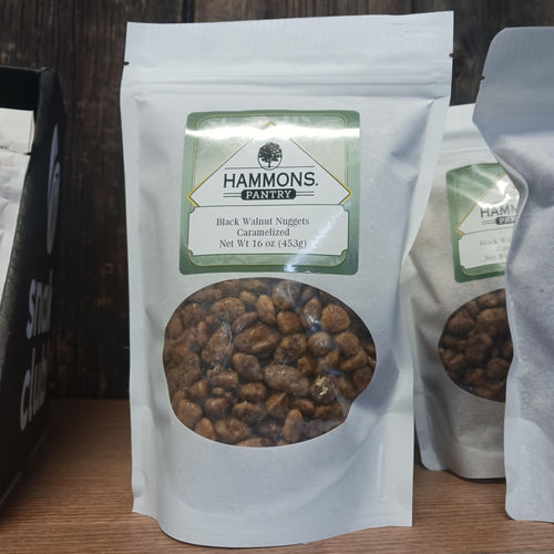 White resealable bag filled with caramelized black walnut nuggets, labeled with Hammons Pantry logo, displayed on wooden surface in Kitchen & Food snacks collection.