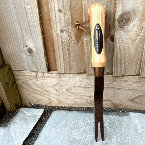 Handcrafted Spear & Jackson grubber with a hammer-finished, powder-coated steel head and smooth natural wooden handle with leather loop, ideal for farm, garden, and lawncare tasks.