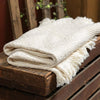 Soft, cream-colored jacquard cotton throw with textured woven blocks and fringed edges, handcrafted in the USA, perfect for Home & Decor and cozy living spaces.