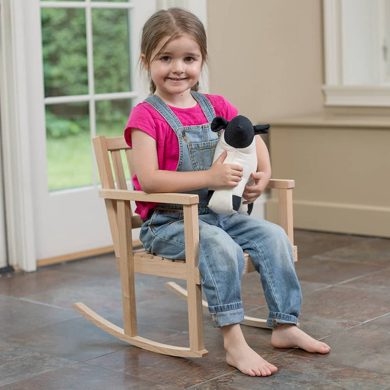 Young girl sitting barefoot on a handcrafted wooden children's rocker made of unfinished oak, holding a stuffed animal, in a bright room with natural light, suitable for Toys, Books & Games, USA Made, Amish Made, Children's Toys, Wooden Toys, Best Sellers, and Promo Eligible collections.