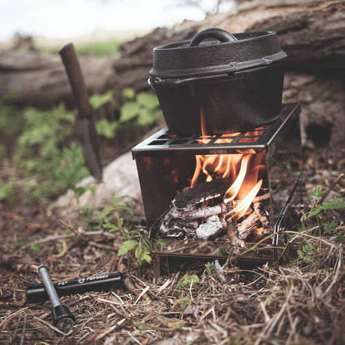 Handcrafted compact camp stove with visible flames burning wood below a black cast iron pot in an outdoor natural setting, ideal for Farm, Garden & Tool, Camping, and Emergency Supplies collections.