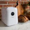 Compact white temperature-controlled device displaying 77°F on a digital screen, placed on a marble countertop next to freshly baked artisan bread and a wooden cutting board, featured in Kitchen & Food and Baking Supplies collections.